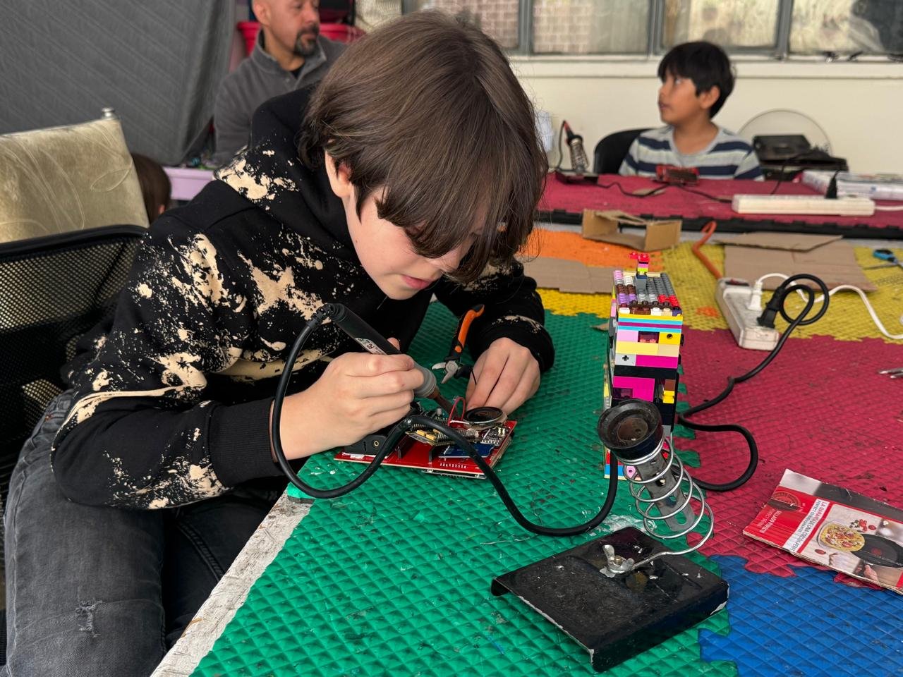 Niño soldando componentes electrónicos en taller Hoky 360